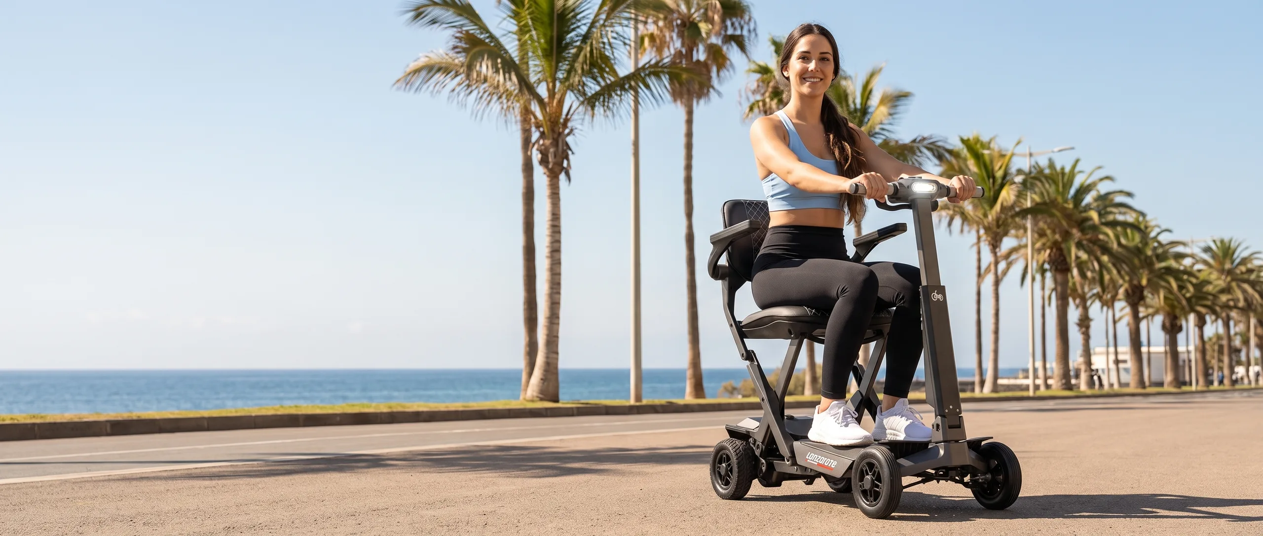 Mujer joven en scooter eléctrico plegable Lanzarote por el paseo marítimo